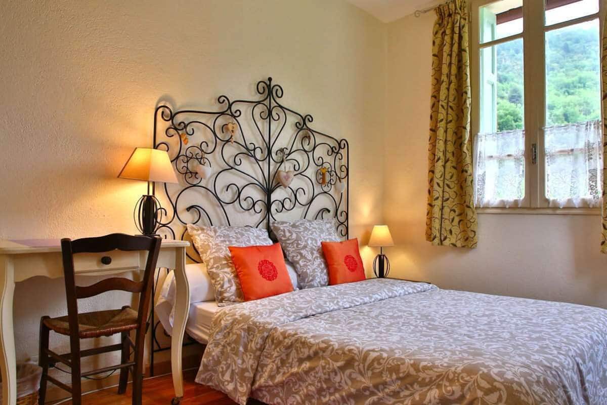 A bedroom with a bed, two bedside lamps, a desk, and a chair.