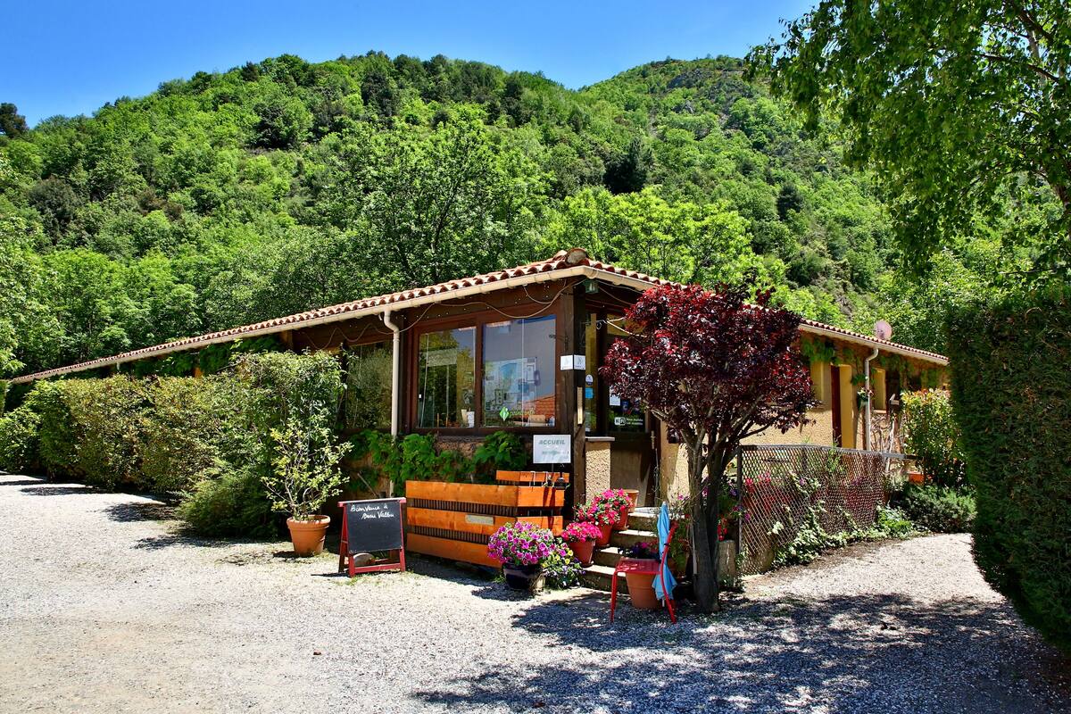 A rustic building with a wooden bench and potted plants in front.