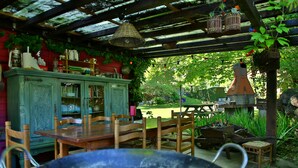 A rustic outdoor dining area with wooden furniture, a green cabinet, and a hanging birdcage. - Beau Vallon - Gîte et Chambres d'Hôtes (Sahorre)