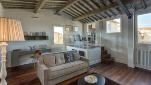 A modern living room with a sofa, a lamp, a dining area, and a staircase leading to an upper level. - Apartments Florence - Beautiful Terrace Serragli (Firenze)