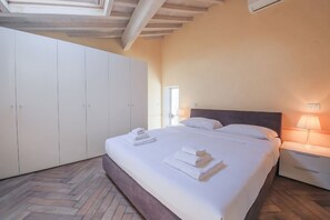 Une chambre à coucher avec un lit, des tables de chevet, une armoire et une fenêtre.