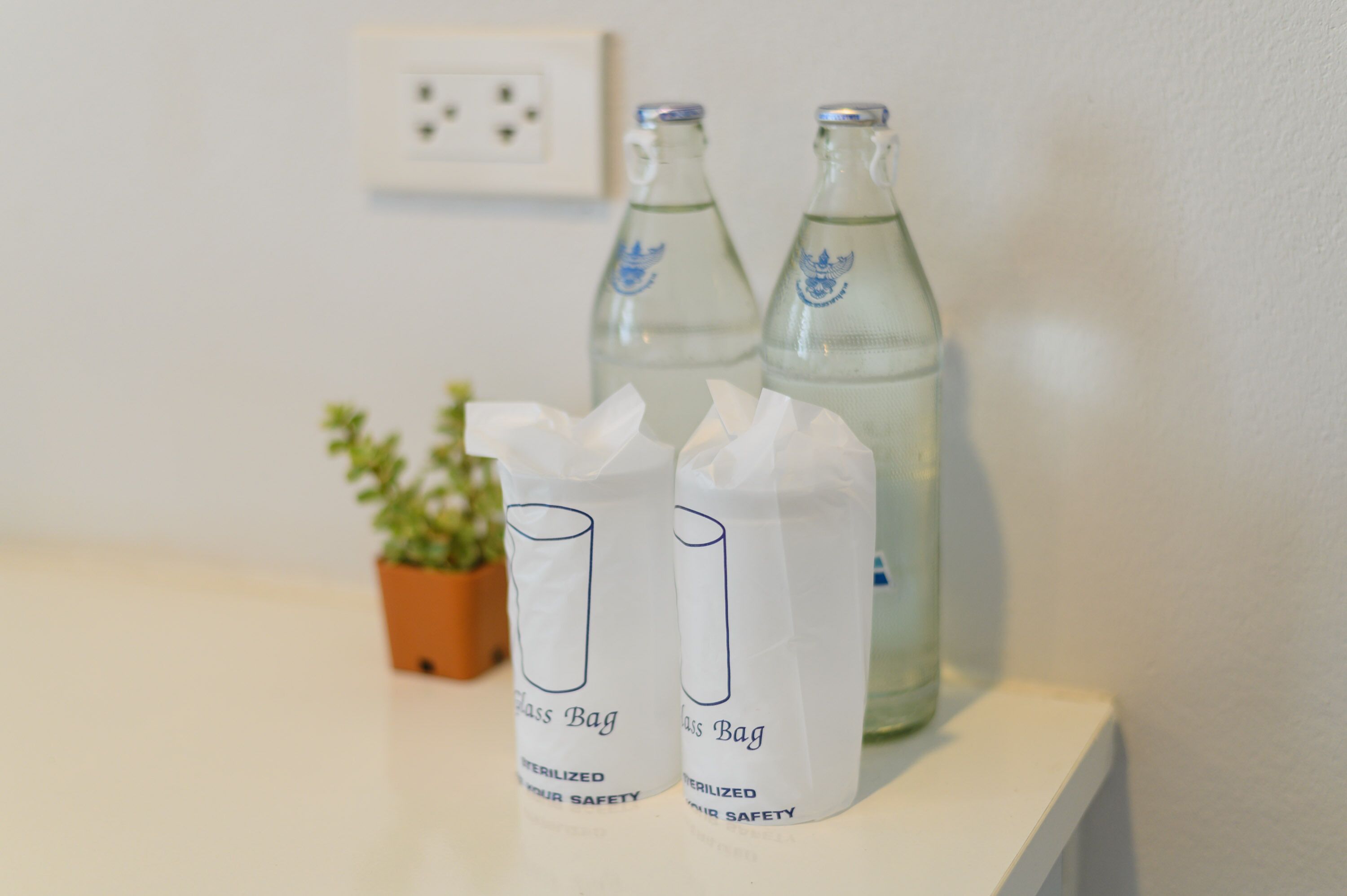 Two glass bottles and two glass bags on a white surface.