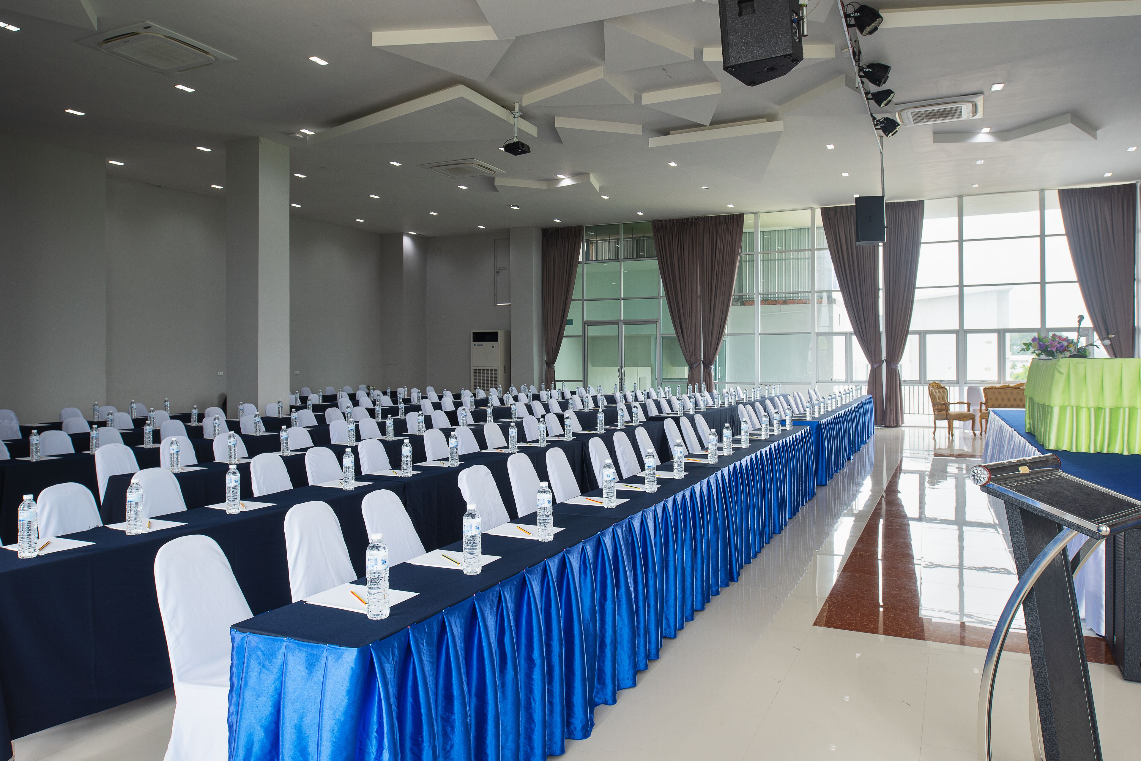 A conference room with rows of tables, chairs, and water bottles.