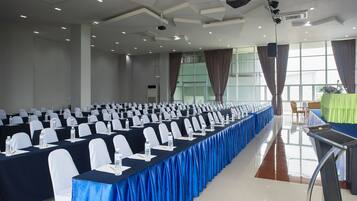 A conference room with rows of tables, chairs, and water bottles.