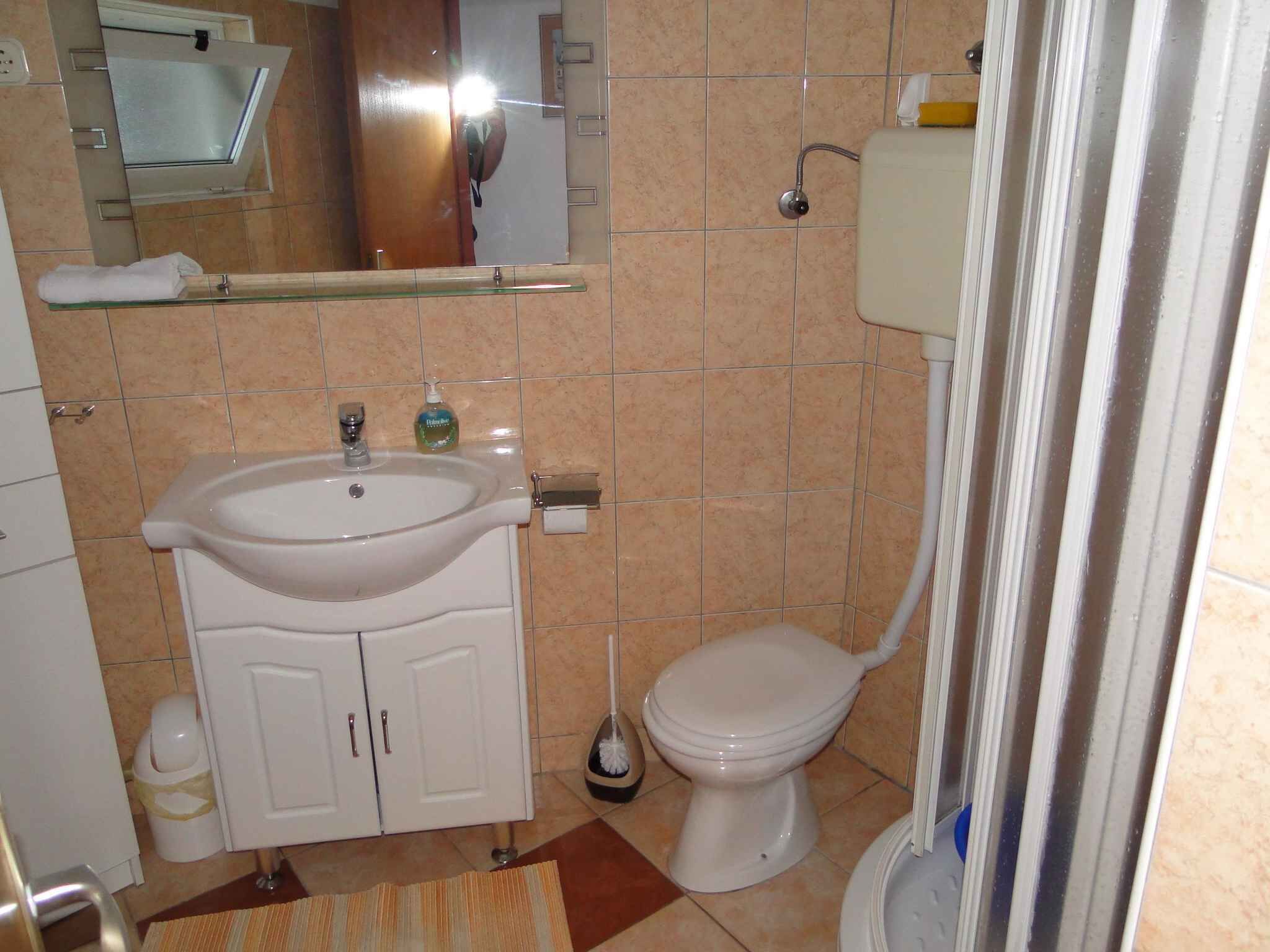 A bathroom with a sink, toilet, and mirror.