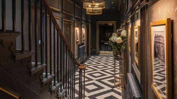 A grand hallway with a checkered floor, a staircase with wooden railings, and framed artwork on the walls. - Edgbaston House (Birmingham)