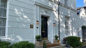 A white building with a black door and steps leading to the entrance. There are two potted plants on either side of the door. - Edgbaston House (Birmingham)
