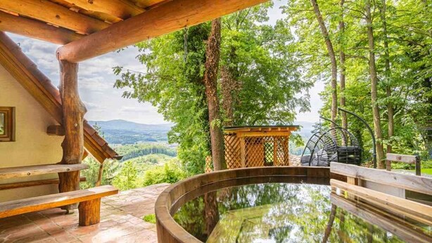 A wooden deck with a hot tub, surrounded by trees and a scenic view of hills. - Studio in the vineyards (Novo Mesto)