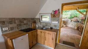 A compact kitchen with a built-in dishwasher, a window, and a stone-tiled backsplash. - Studio in the vineyards (Novo Mesto)