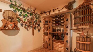 A rustic wine cellar with wooden shelves, barrels, and a wall-mounted wine rack. - Studio in the vineyards (Novo Mesto)