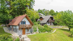 A rustic cabin with a stone foundation, wooden exterior, and a red-tiled roof. - Studio in the vineyards (Novo Mesto)