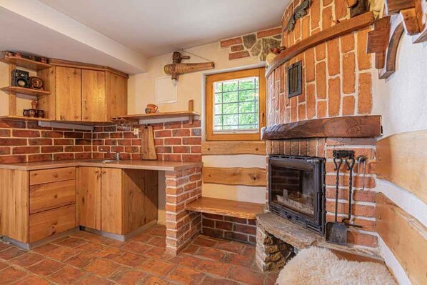 Una cocina con chimenea de ladrillo, armarios de madera y una ventana.