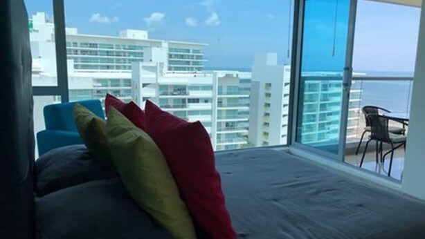 A bedroom with a large window overlooking a cityscape and the sea. - Apartamento de Lujo Frente al Mar (Cartagena)
