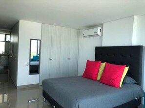 Un dormitorio moderno con una cama grande, cabecera negra y armario blanco.