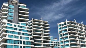 A modern multi-story hotel with a prominent logo on the top. - Apartamento de Lujo Frente al Mar (Cartagena)