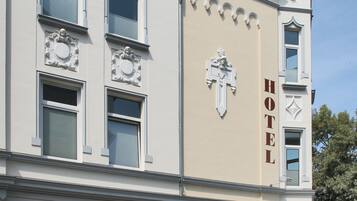 A hotel with a prominent cross emblem, multiple windows, and a classic architectural design.
