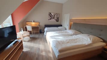 Una habitación de hotel con una cama grande, un escritorio, una silla, un televisor y un cuadro en la pared.