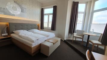 Ein Hotelzimmer mit Bett, Nachttisch, Lampe, Stuhl und einem kleinen Tisch mit einer Flasche.