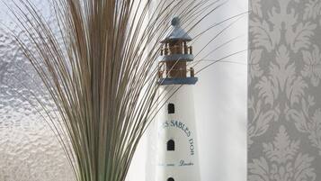 Un modelo de faro con texto en el lateral, colocado junto a una ventana con cortina estampada.