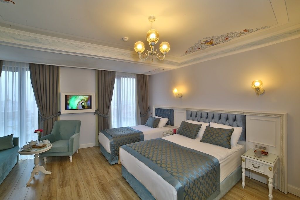 A hotel room with two beds, a sitting area with a chair, a small table, and a television.
