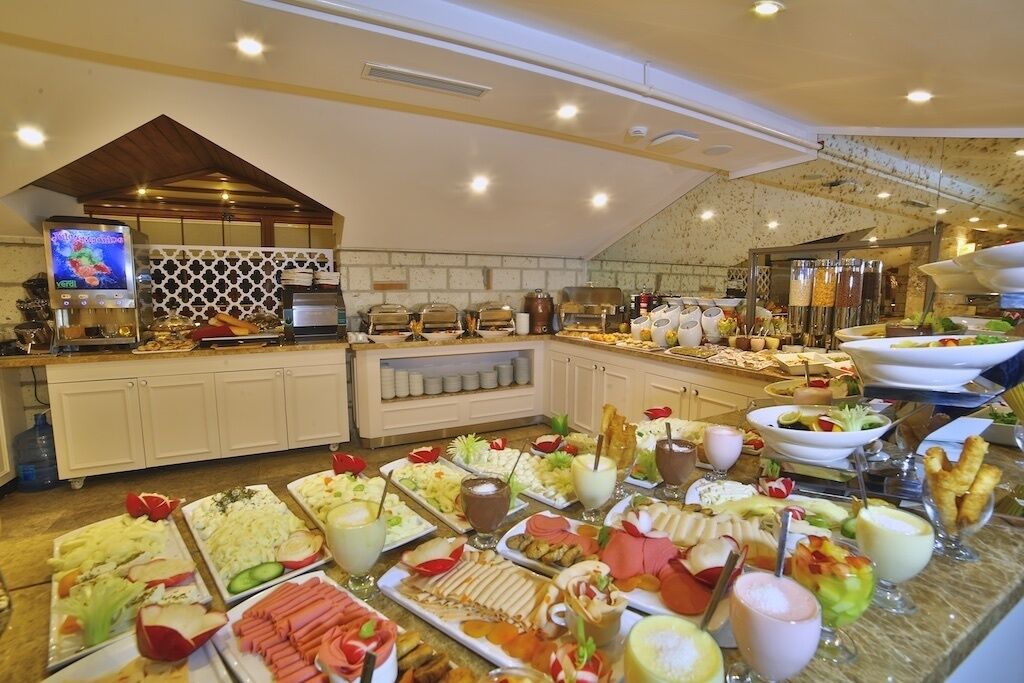 A buffet with various food items and beverages, a coffee machine, and a TV screen.
