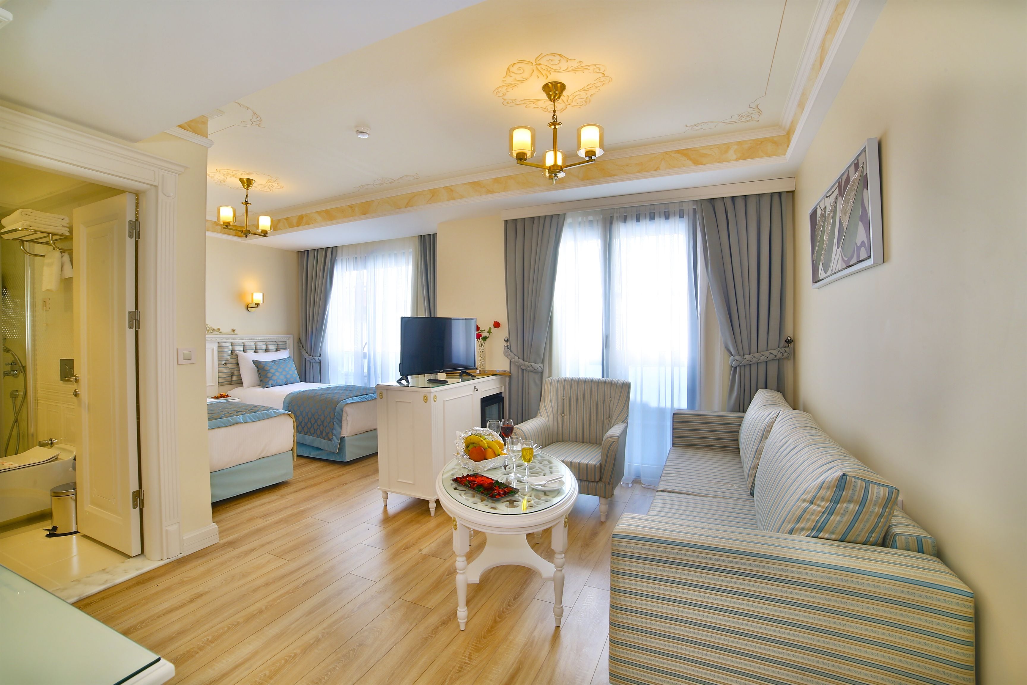 Una habitación bien iluminada con una cama, un sofá, una mesa de comedor y un televisor.
