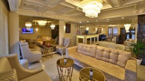 Een ruime lobby met een comfortabele bank, fauteuils en een bar.