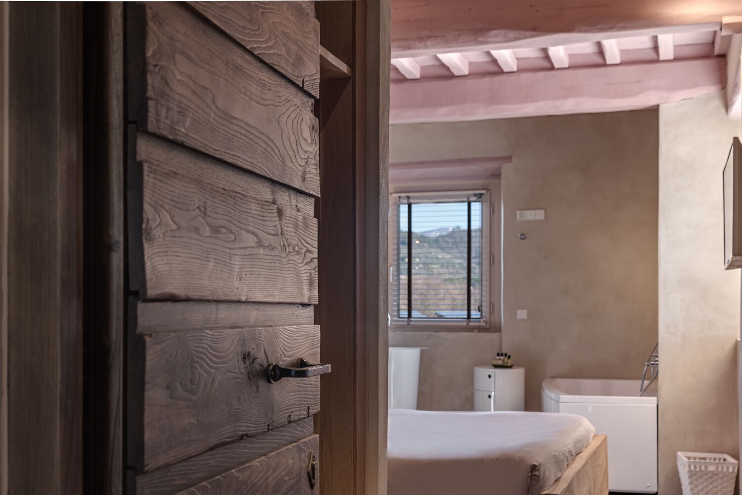 Una camera da letto con un'armadio in legno, una finestra con vista, un letto bianco e un comodino bianco.