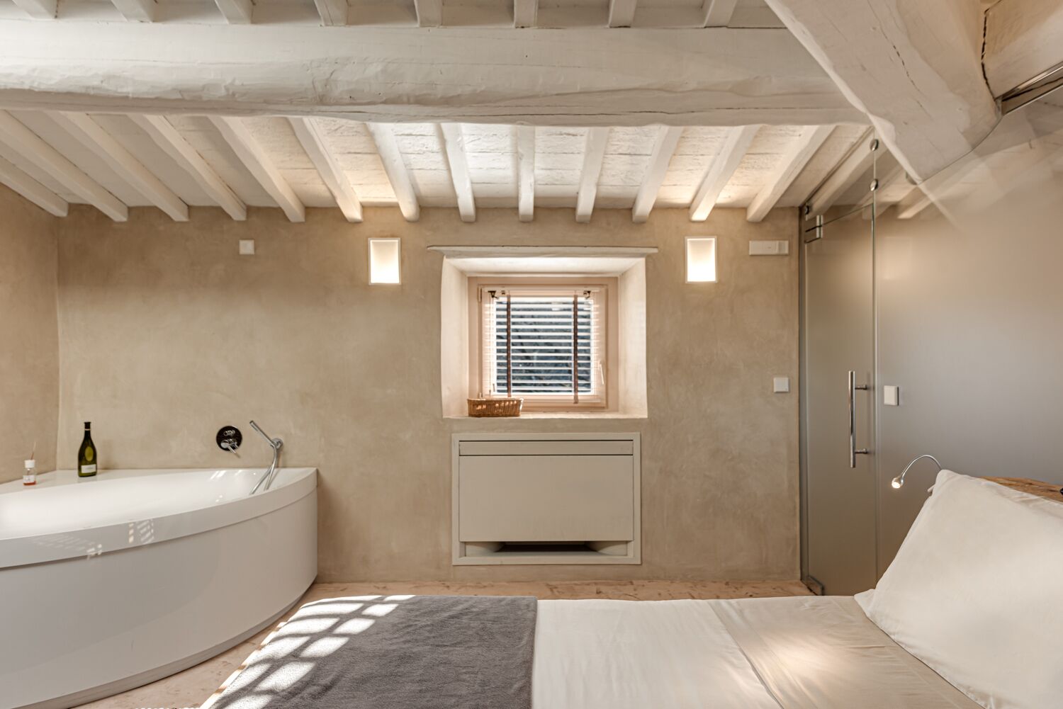 A modern bathroom with a freestanding bathtub, a window with blinds, and a built-in heater.