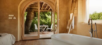 Un baño con bañera, ducha y puerta de vidrio que da a un área de estar al aire libre.