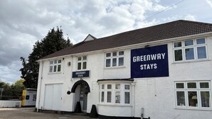 Ein zweistöckiges Gebäude mit einem Schild, auf dem 'Greenway Stays' steht.