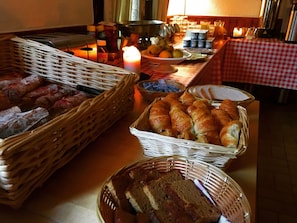 A buffet table with various food items including bread, pastries, and a cake. - Au Bon Accueil (Les Deux Alpes)