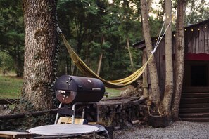 A hammock tied between trees, a grill, and a rustic wooden structure. - Au Bon Accueil (Les Deux Alpes)