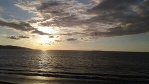 A sunset over a calm sea with a distant landmass. - Drake Lapas (Drake Bay)