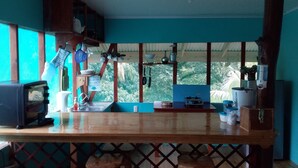 A kitchen with a wooden counter, a sink, and a window overlooking greenery. - Drake Lapas (Drake Bay)