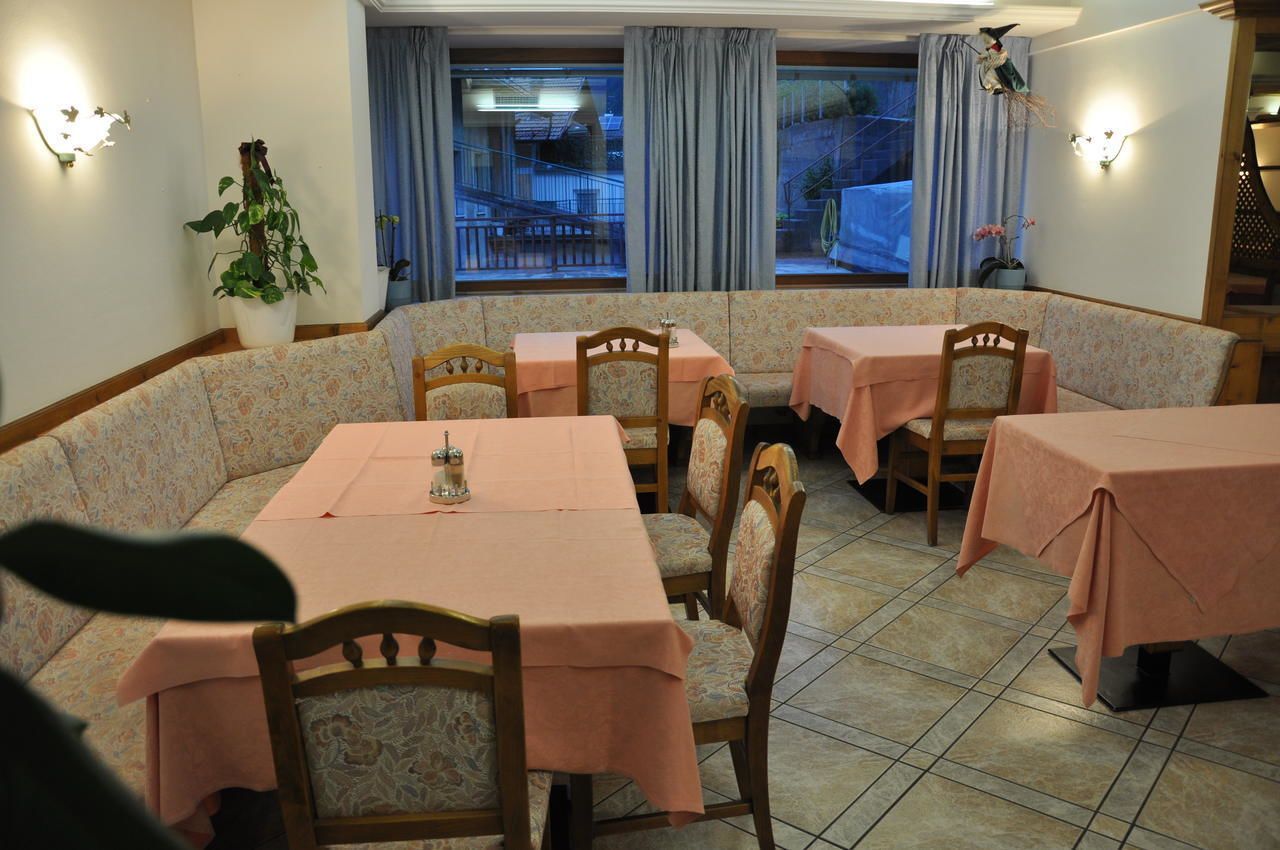 A dining area with a long table and several chairs, covered with pink tablecloths.