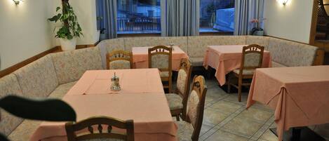 A dining area with a long table and several chairs, covered with pink tablecloths.