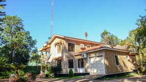 A two-story house with a stone facade, a tiled roof, and a garage. - Mama Thea Homes - Hostel (Moshi)