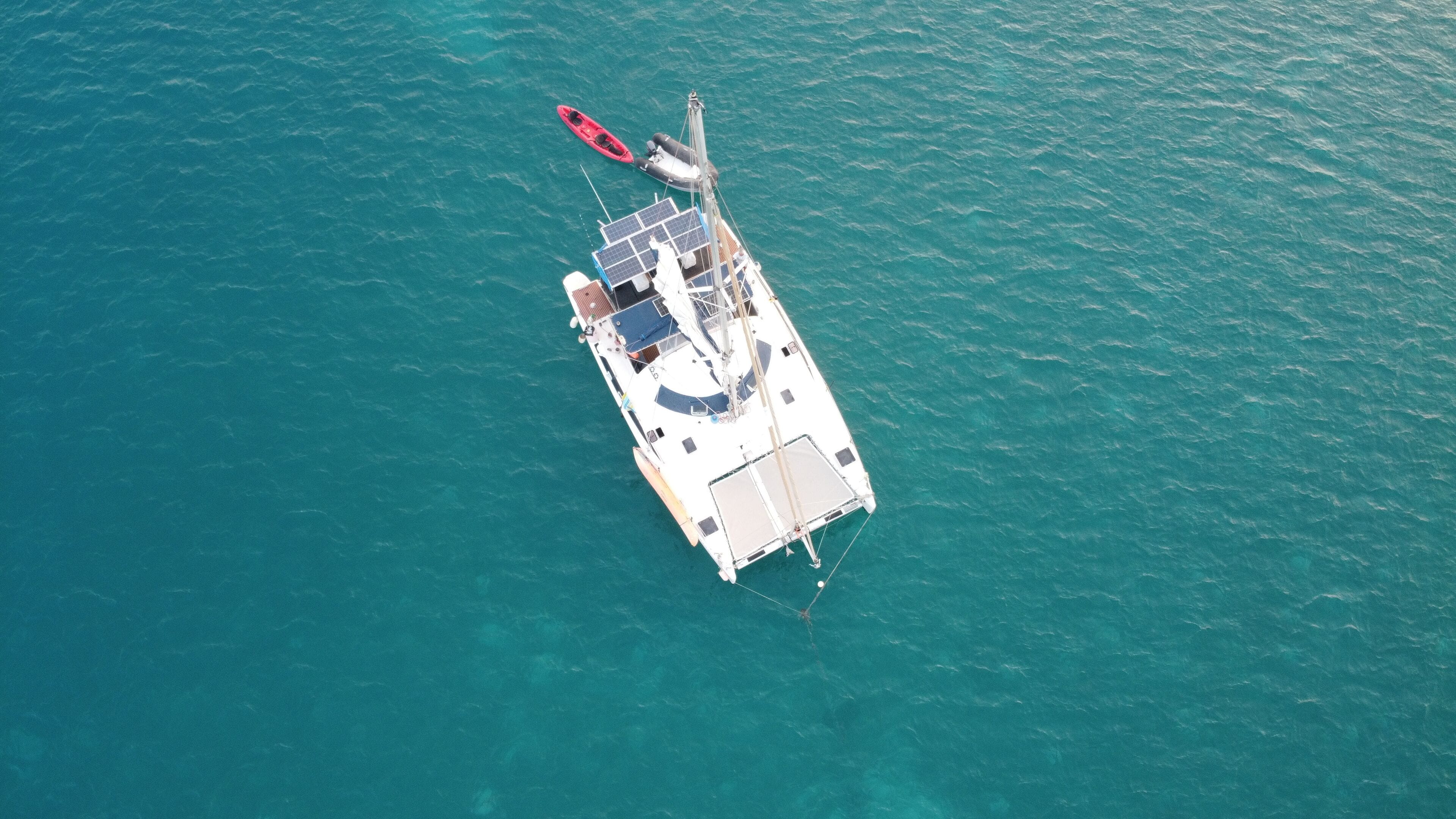 An aerial view of a sailboat with a cabin, deck, and a red dinghy.