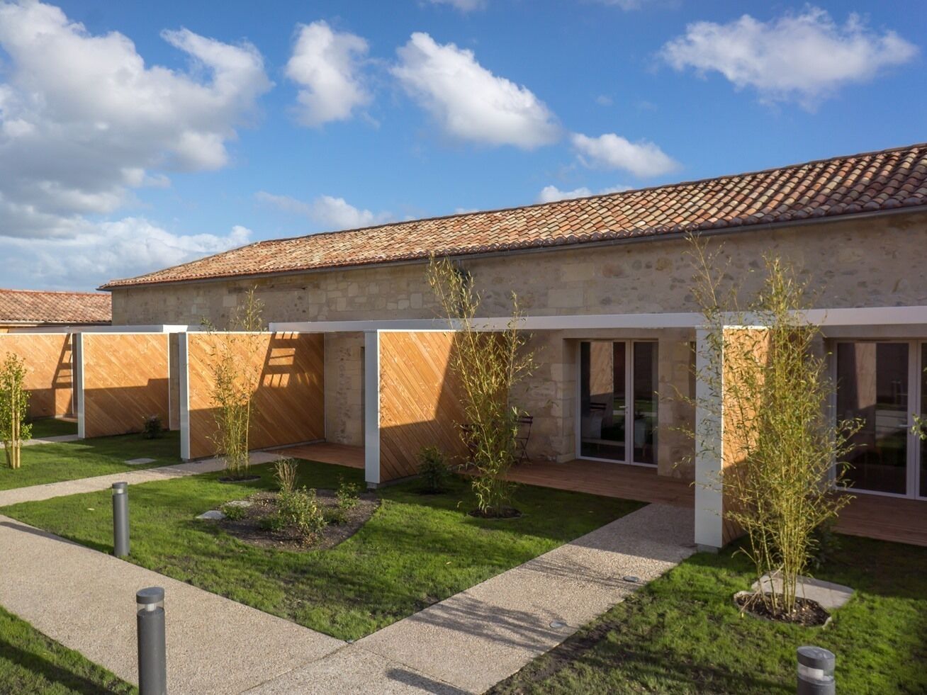 A modern building with a tiled roof, a covered outdoor area with seating, and a well-maintained lawn.