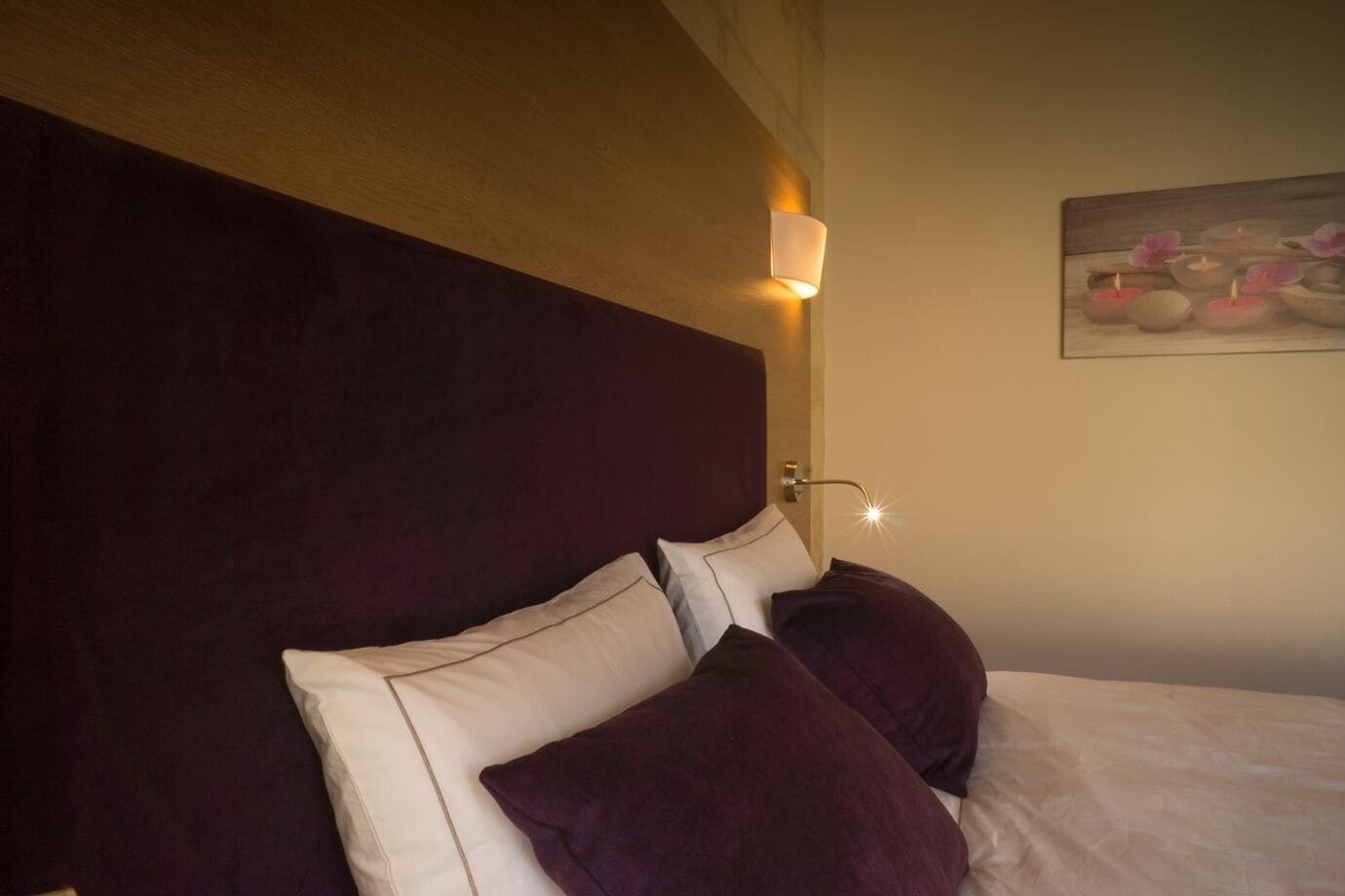A hotel room with a large bed, a headboard, and a wall-mounted light fixture.