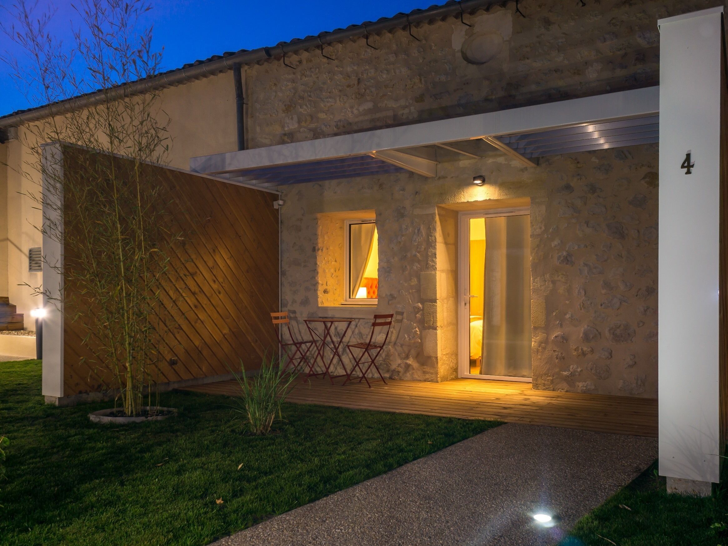 A modern house with a stone facade, a wooden deck, and a small garden.