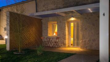 A modern house with a stone facade, a wooden deck, and a small garden.