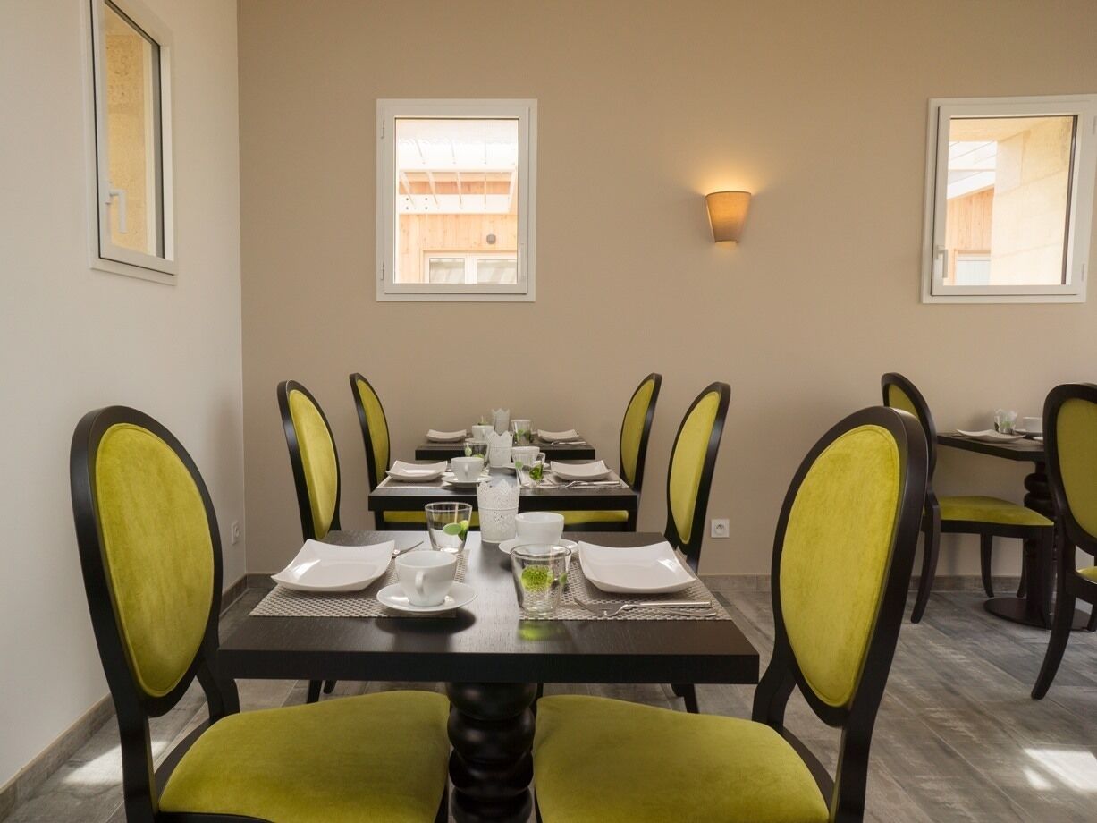 Comedor con una mesa rectangular dispuesta para cuatro personas, rodeada de sillas con cojines amarillos.