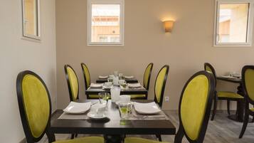 Comedor con una mesa rectangular dispuesta para cuatro personas, rodeada de sillas con cojines amarillos.