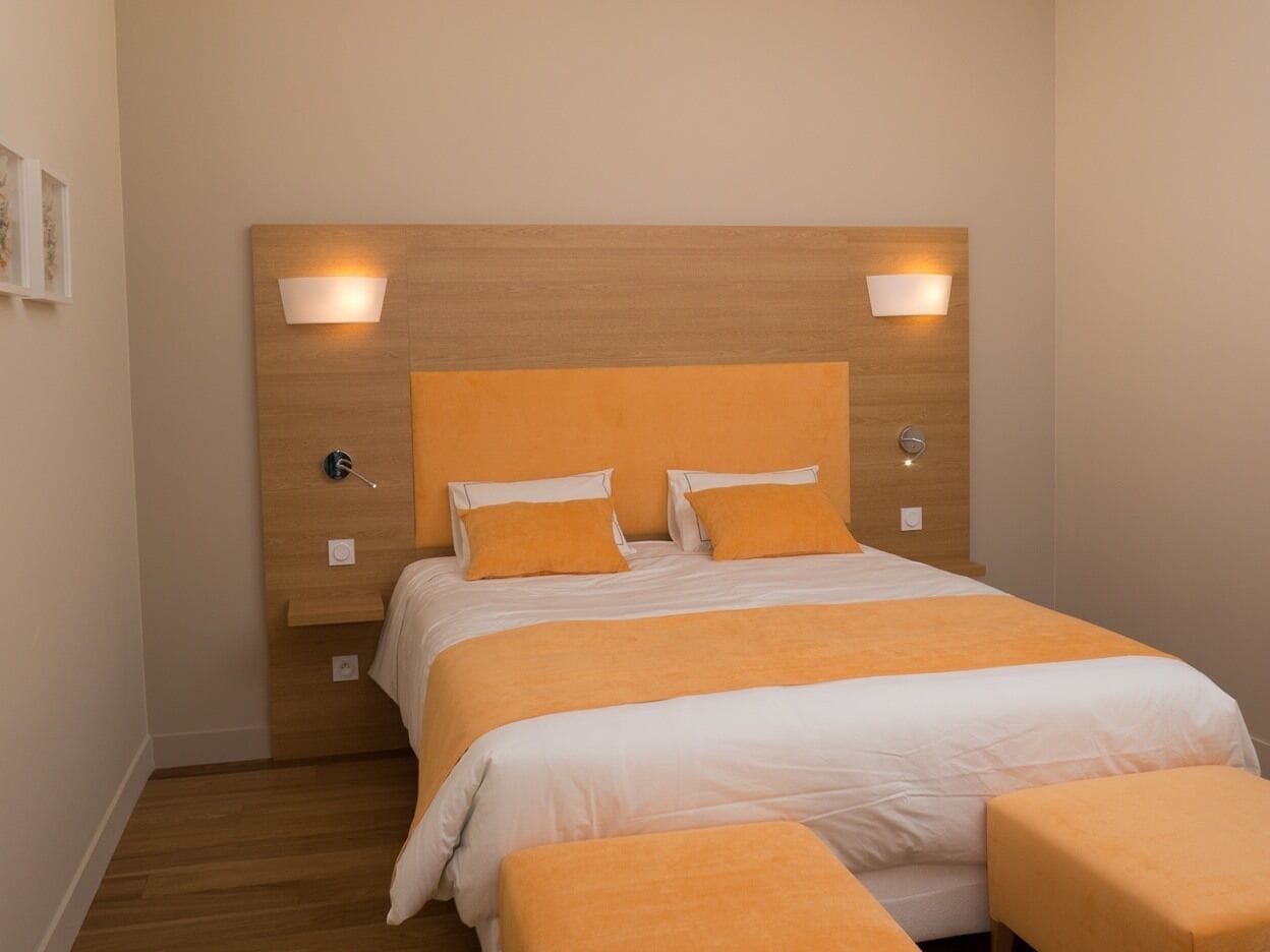 Une chambre d’hôtel bien aménagée, avec un grand lit, deux tables de chevet et des lampes fixées au mur.