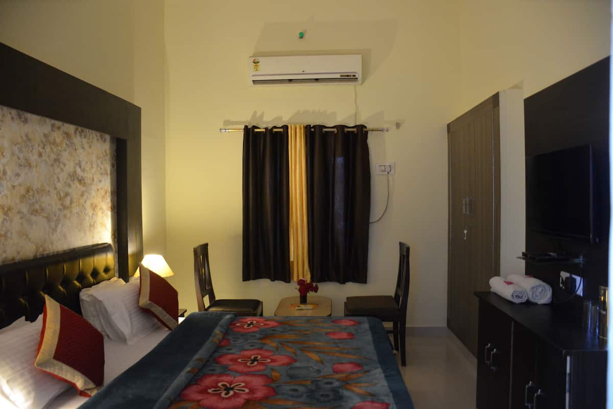 Une chambre d’hôtel équipée d’un lit, d’un bureau, d’une chaise, d’une télévision et d’un appareil de climatisation.