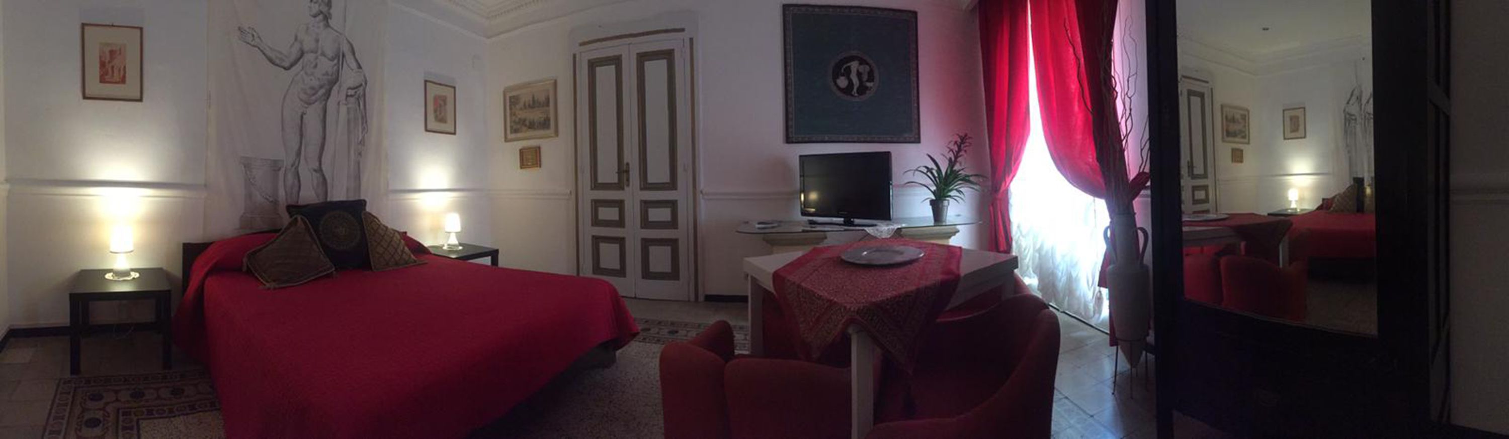 Ein Hotelzimmer mit Bett, Schreibtisch, Stuhl, Fernseher und einem fensterbepflanzten Fenster.