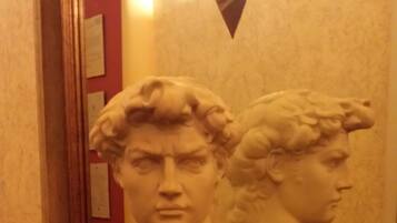 A bust sculpture on a shelf with a mirror reflecting it.