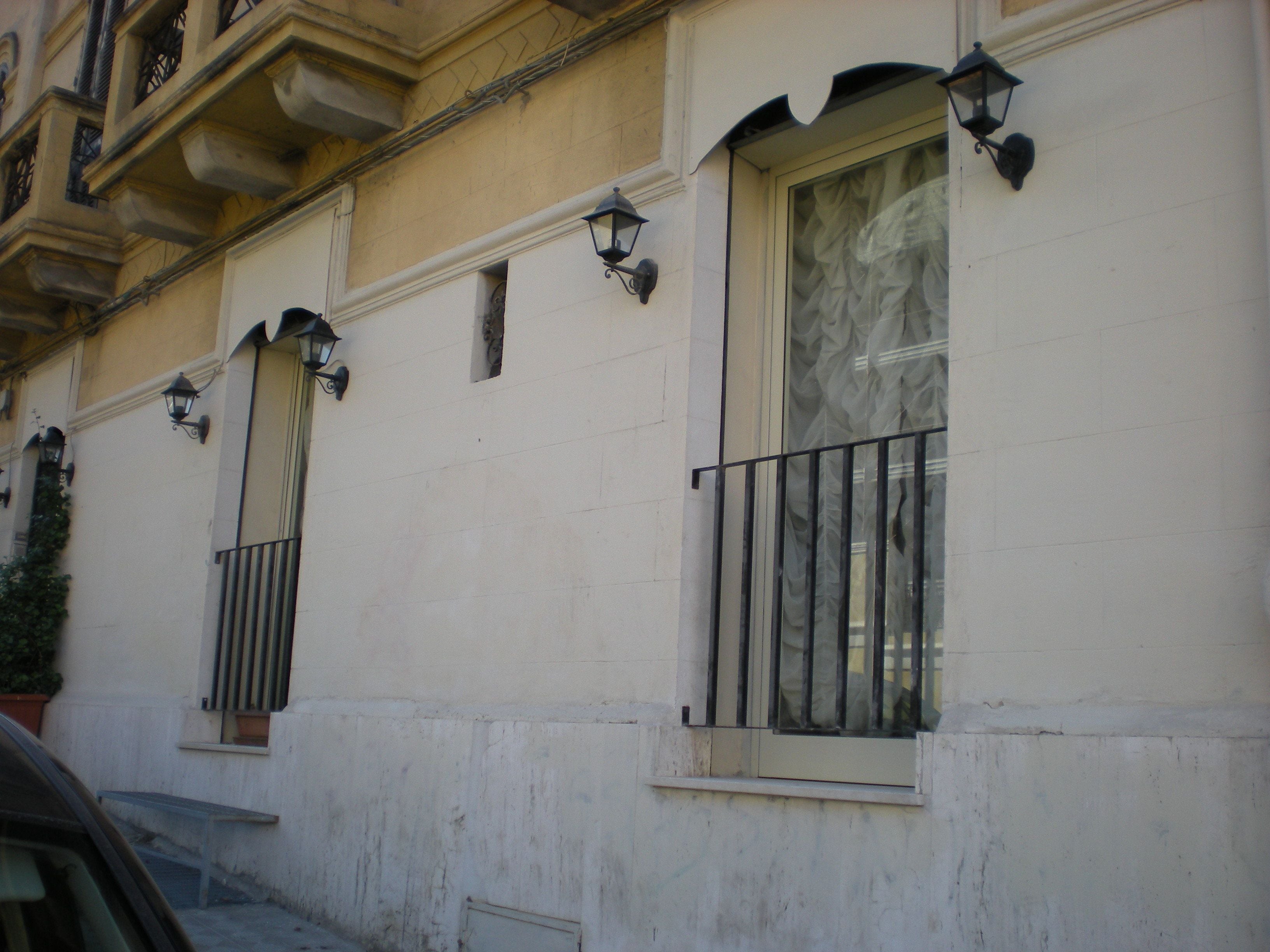 A building with multiple windows, some with metal railings, and a few with decorative lanterns.